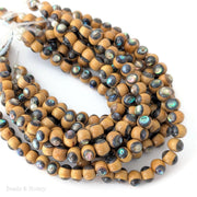String of golden brown wood beads inlaid with multicolored abalone shell on a white background.